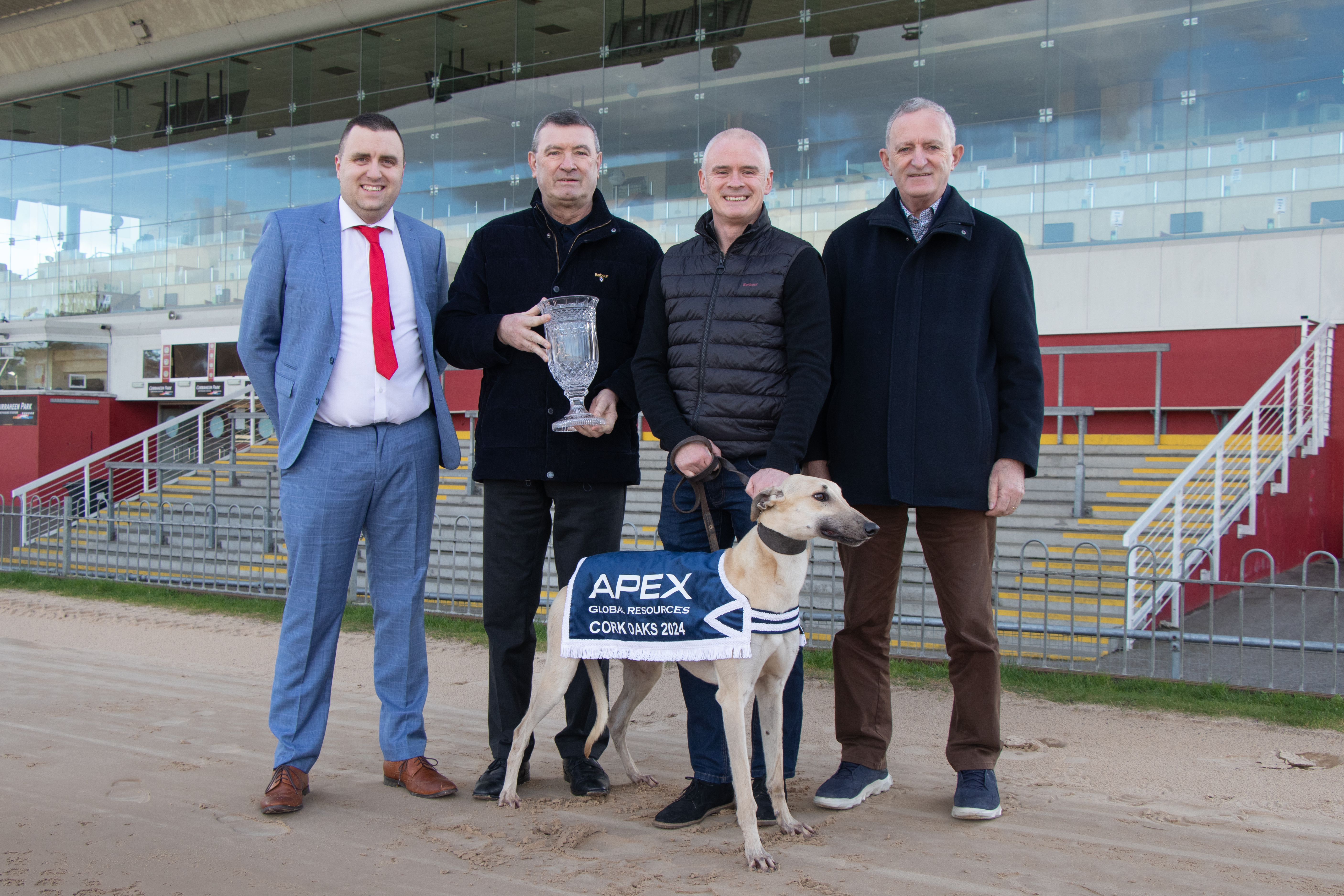 Image shows 4 men and a greyhound pictured to launch the 2024 Apex Global Resources Cork Oaks at Curraheen Park Greyhound Stadium 